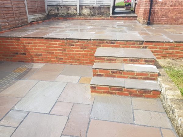 Sandstone patio with brick walling in Acrise